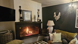 Un saló acollidor amb una llar de foc, un sofà, una làmpada i objectes decoratius a la llesta.