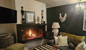 A cozy living room with a fireplace, a sofa, a lamp, and decorative items on the mantel. - The Lily House Hermanus (Hermanus)