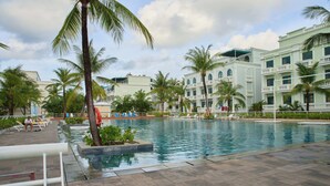 A swimming pool with palm trees, lounge chairs, and a building with balconies. - Viona Beach Hotel - Marina Phu Quoc (Phu Quoc)