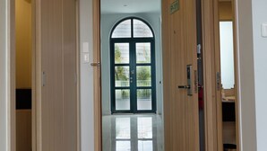 A hallway with wooden flooring, a white mat, and a door with a number sign. - Viona Beach Hotel - Marina Phu Quoc (Phu Quoc)