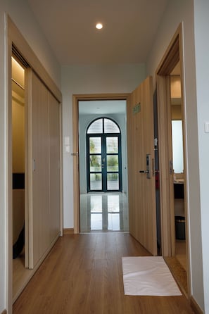 A hallway with wooden flooring, a white mat, and a door with a number sign. - Viona Beach Hotel - Marina Phu Quoc (Phu Quoc)