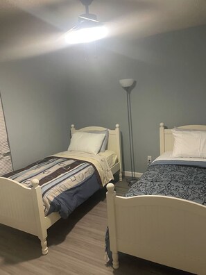 Ein Schlafzimmer mit zwei Einzelbetten, einer Stehlampe und einer Deckenleuchte.