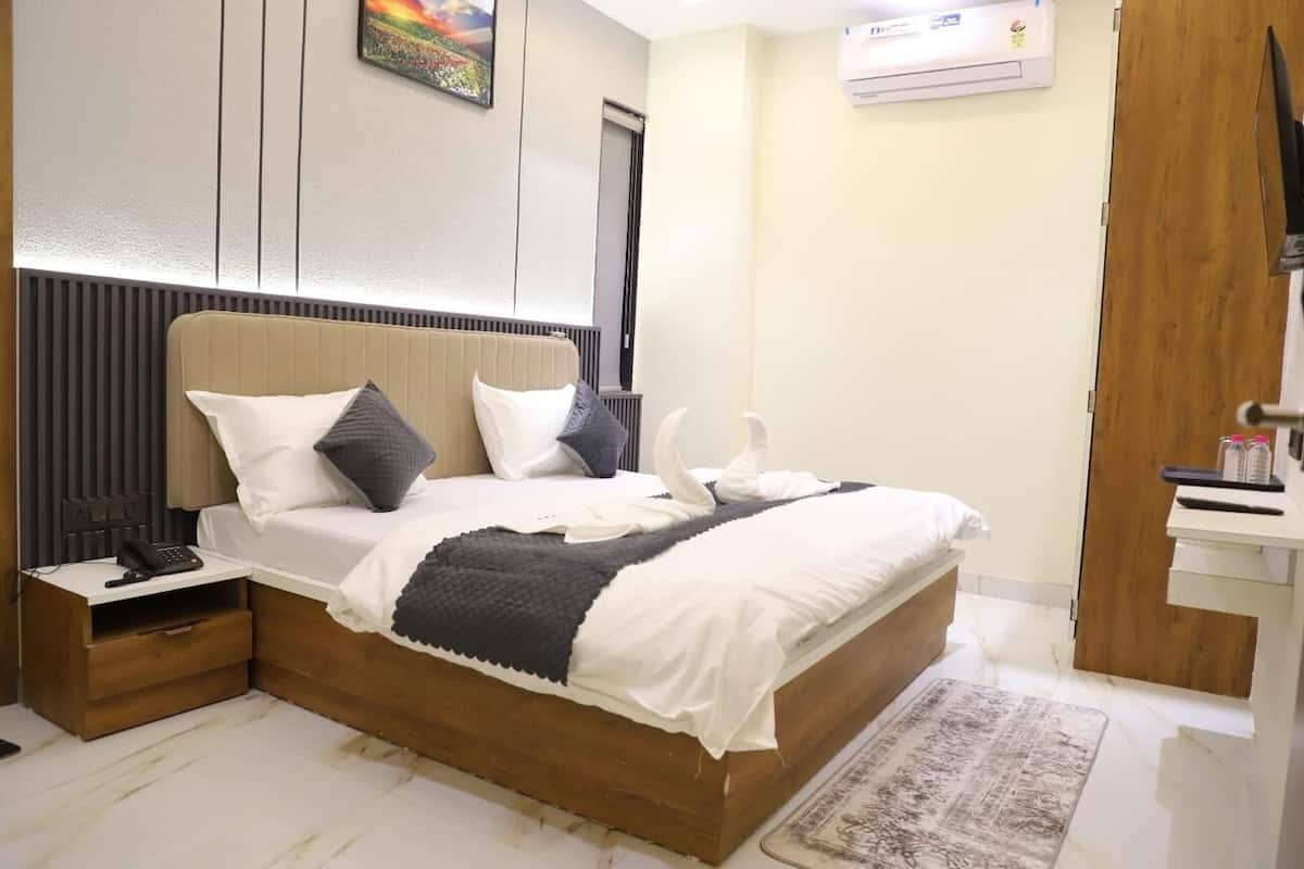 Una habitación de hotel moderna con una cama grande, mesitas de noche, un escritorio y un aire acondicionado instalado en la pared.