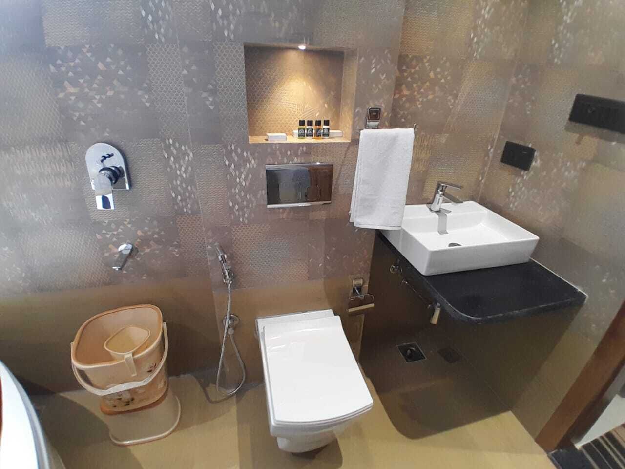 A bathroom with a white sink, a toilet, a shower, and a towel rack.