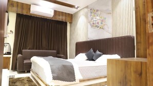 A modern bedroom with a bed, a chair, a desk, and an air conditioning unit. - Moresta Ajmer Hotel with Rooftop Bar (Ajmer)