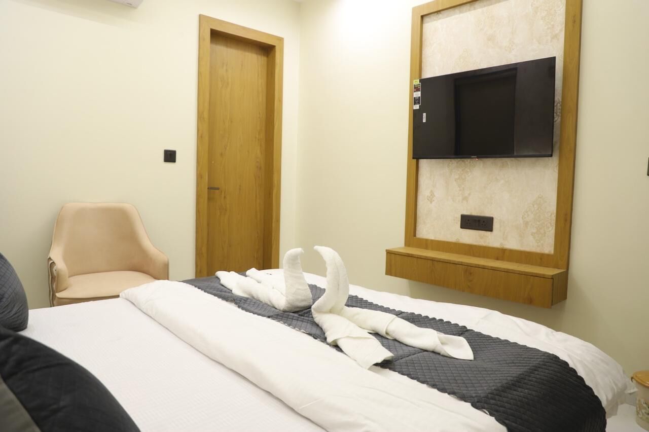 Una habitación de hotel con una cama, una silla, una puerta de madera y un televisor montado.