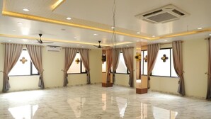 A spacious room with a marble floor, ceiling fans, and large windows with curtains. - Moresta Ajmer Hotel with Rooftop Bar (Ajmer)