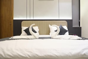 Una cama bien hecha con cabecera, almohadas y manta.