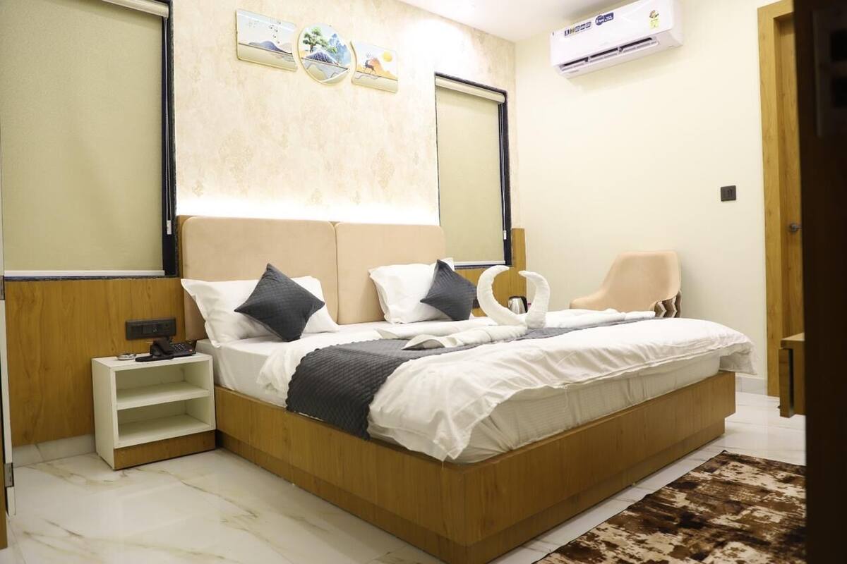 Un dormitorio moderno con cama de madera, mesitas de noche, una silla y aire acondicionado de pared.