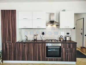 A modern kitchen with wooden cabinets, a gas stove, an oven, and a backsplash with patterned tiles. - Apartment Melba by Interhome (Civezza)