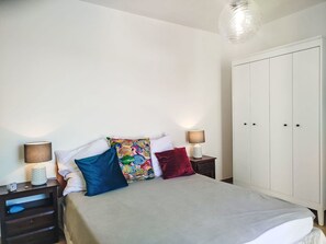 A bedroom with a bed, two bedside tables, a nightstand, a wardrobe, and a hanging light fixture. - Apartment Melba by Interhome (Civezza)
