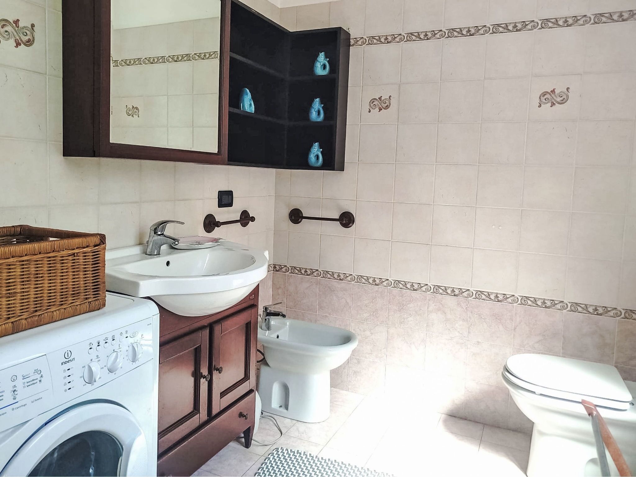 A bathroom with a washing machine, a sink, a bidet, and a toilet.