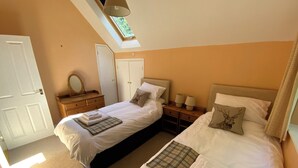 Ein Schlafzimmer mit zwei Betten, einem Oberlicht, einem Kleiderschrank und einem Nachttisch mit Lampen.