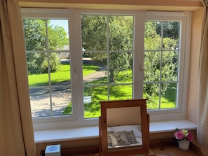 A room with a large window overlooking a green landscape. - Swallows Cottage (Saint Giles on the Heath)