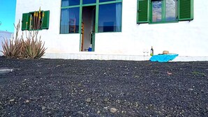 Um edifício com persianas verdes, uma janela grande e uma lona azul no chão.