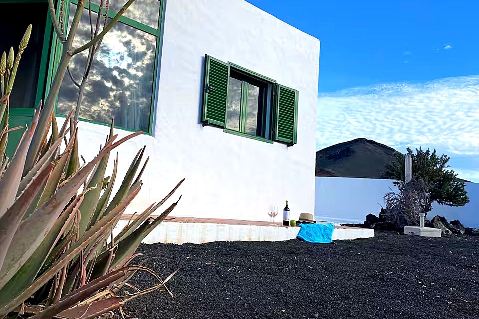 Un edificio moderno blanco con contraventanas verdes, cobertura de suelo negra y cielo despejado.