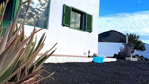 Um edifício moderno branco com persianas verdes, cobertura de solo preta e céu claro.