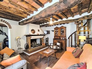 Un interior rústico con chimenea, muebles de madera y una escalera.