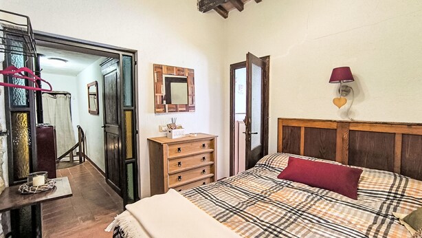 Una camera da letto con un letto, una cassettiera, uno specchio e una porta che dà su un'altra stanza.