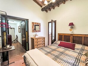 A bedroom with a bed, dresser, mirror, and a door leading to another room. - Shelter in the heart of Tuscany by Interhome (Prata)
