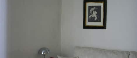A room with a beige sofa, a small side table with a lamp, and a framed picture on the wall.