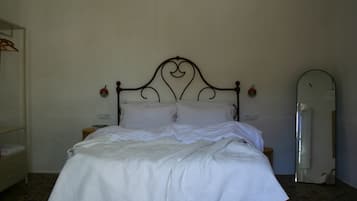 A neatly made bed with a headboard, a bedside table with a lamp, and a mirror on the wall.