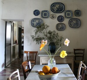 Een eethoek met een tafel voor vier personen, een vaas met bloemen en een fruitschaal.