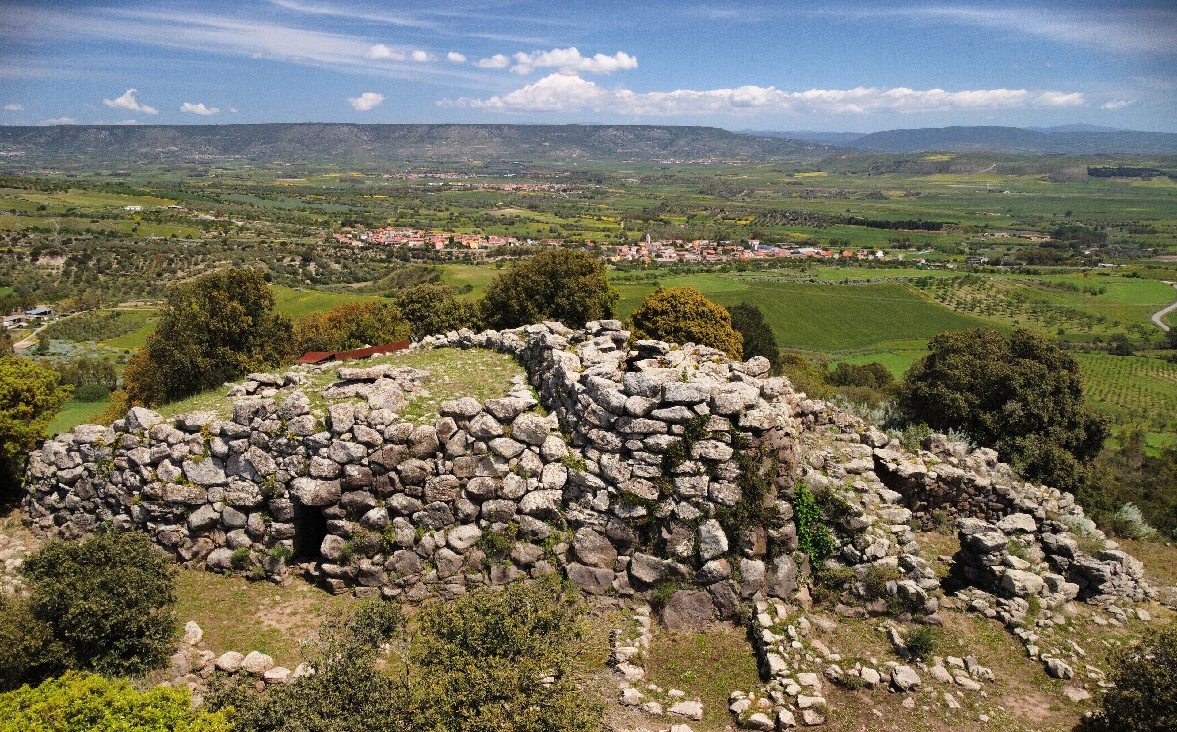 Eine steinerne Ruine mit Blick auf eine ländliche Landschaft und entfernte Gebäude.