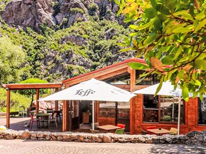 A restaurant with outdoor seating, a stone wall, and a mountainous backdrop. - Sardinia Hillside Retreat – Apt 13, 2BR by Interhome (Valledoria)