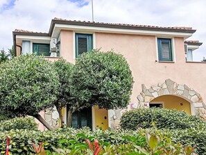 A building with a stone archway, a pink facade, and green shutters. - Sardinia Hillside Retreat – Apt 13, 2BR by Interhome (Valledoria)
