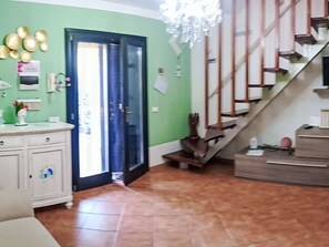 A room with a green wall, a white cabinet, a staircase, and a door leading outside. - Sardinia Hillside Retreat – Apt 14 by Interhome (Valledoria)