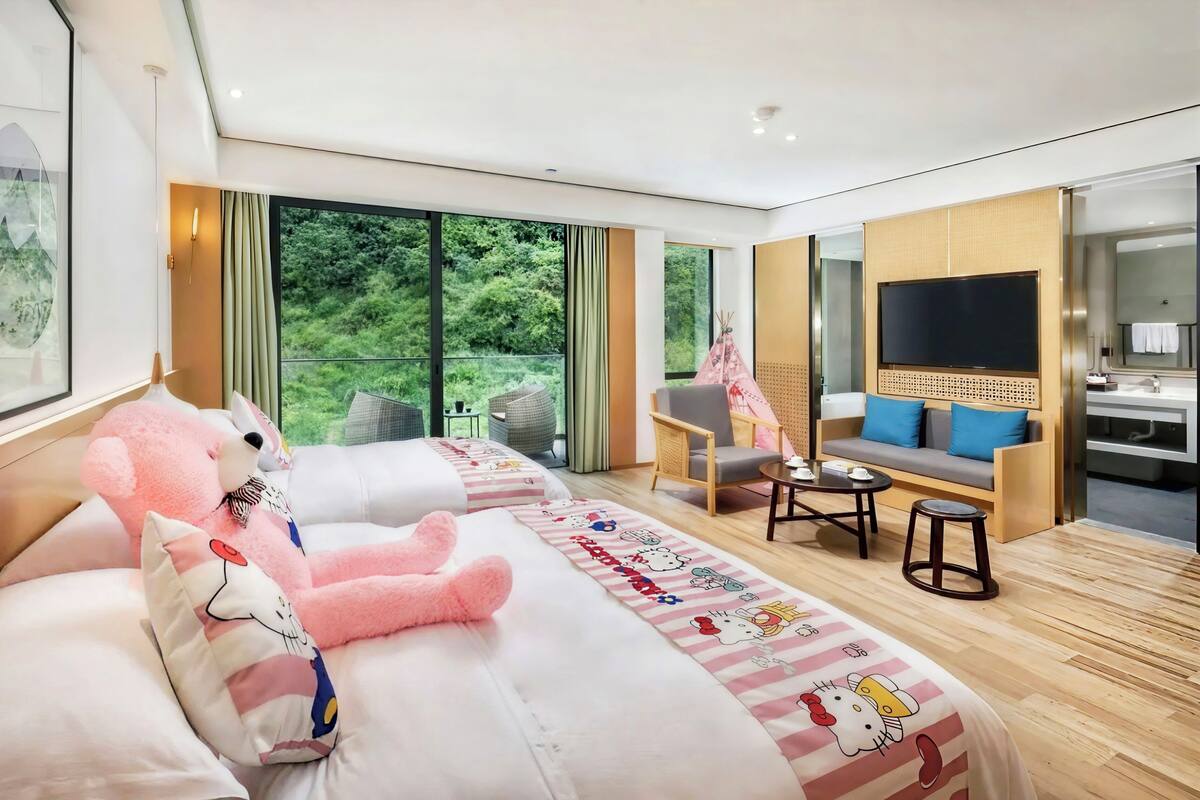 Habitación de hotel con una cama grande, un sofá, un televisor y vistas a zonas verdes.