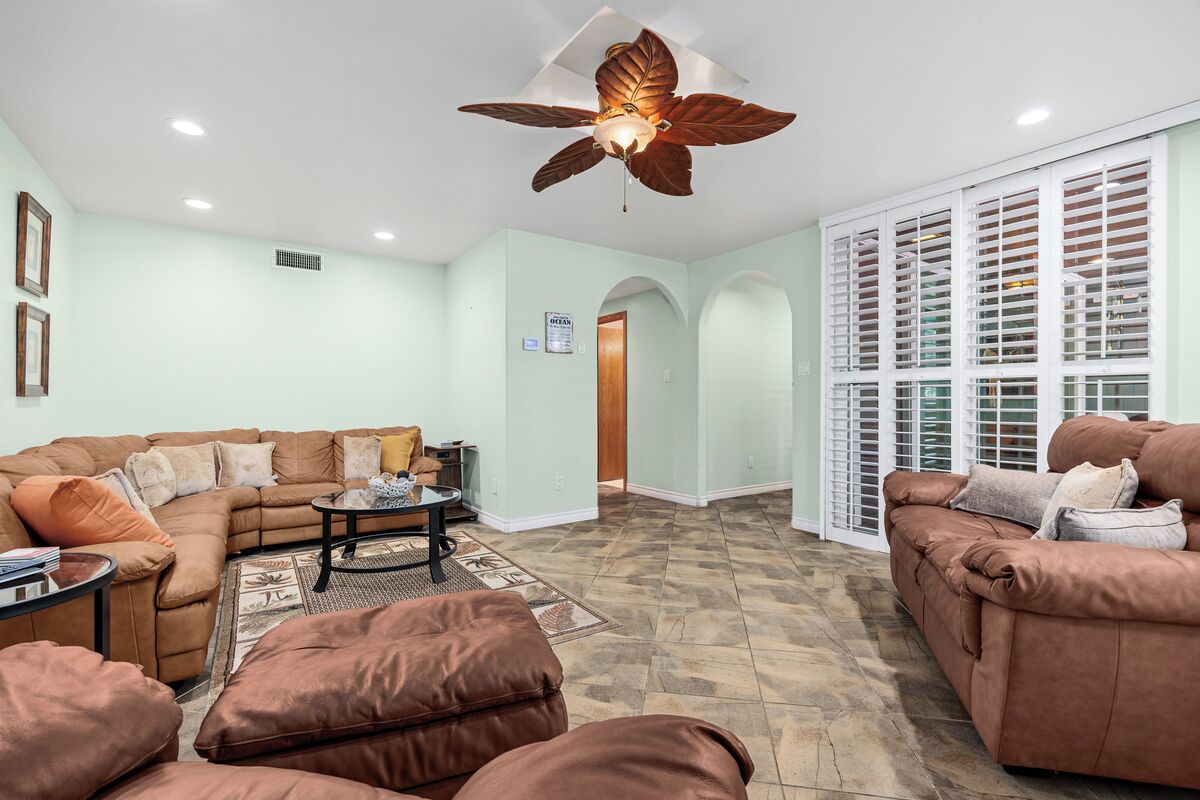 A living room with a sectional sofa, a coffee table, and a ceiling fan.