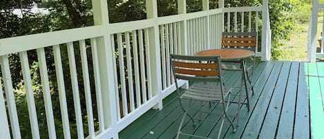Een overdekte veranda met een groene vloer, witte leuningen en een tafel met stoelen.