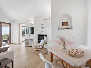 Ein modernes Wohnzimmer mit einer Couch, einem Esstisch mit Stühlen, einem Kamin und einem Fernseher.