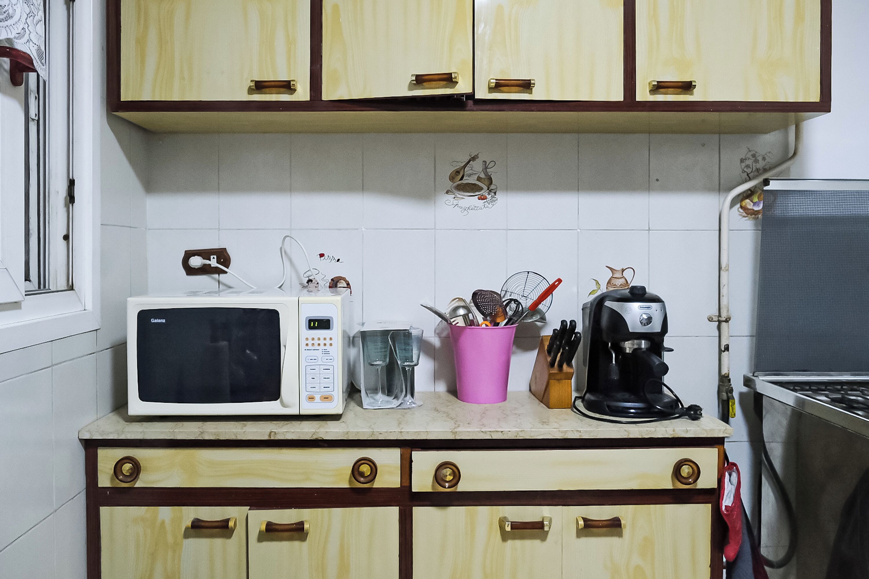 Une cuisine équipée d’un four à micro-ondes, d’une machine à café et d’ustensiles de cuisine, le tout posé sur le plan de travail.