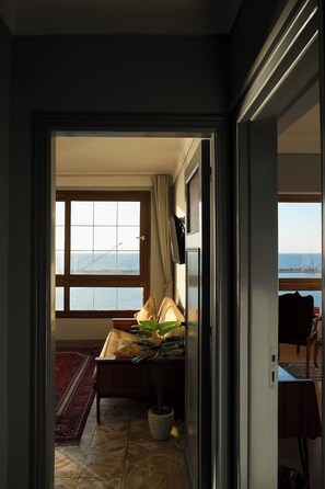 Una habitación con un ventanal grande, una cama, una planta en maceta y vistas al mar.