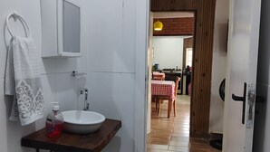 Un baño con lavamanos, espejo, toalla y artículos de aseo.