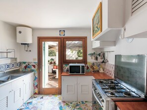 Une cuisine de taille réduite, équipée d’une cuisinière, d’un four à micro-ondes et d’un plan de travail recouvert de carreaux.