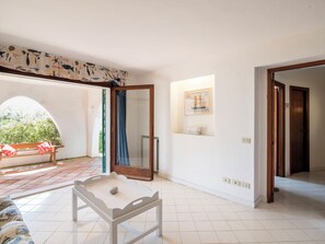 A room with a bench, a table with a stone, a door, and a framed picture on the wall.