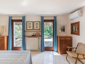 A room with a bed, a chair, a radiator, a shelf with books, framed fish pictures, and a window with curtains. - Villa Delfino by Interhome (San Felice Circeo)