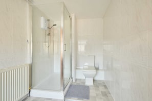 A bathroom with a glass-enclosed shower, a toilet, and a radiator. - Host Stay Roseberry Avenue (Skegness)
