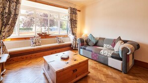 Een gezellige woonkamer met een bank, een houten kist en een raam met gordijnen.
