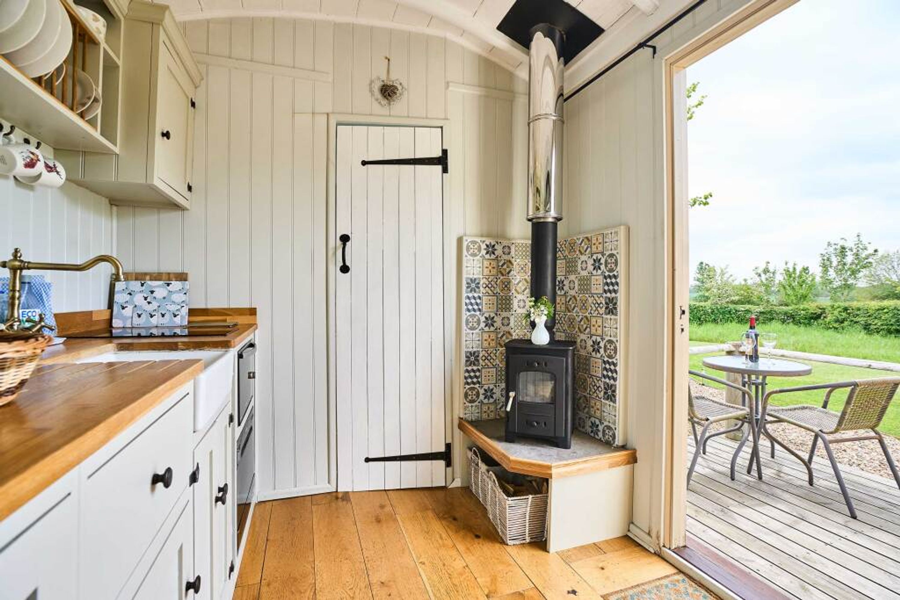 A kitchen with white cabinetry, a wooden countertop, a stove, and a view of the outdoors.