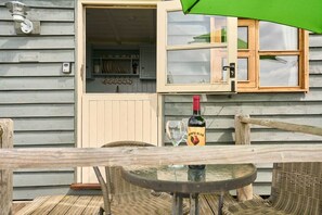 A wooden house with a visible kitchen area, a bottle of wine, and outdoor furniture. - Host Stay Shepherds View (Harleston)