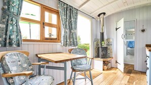 Una cocina acogedora con suelo de madera, una mesa de comedor, dos sillas, una estufa y una ventana con cortinas.