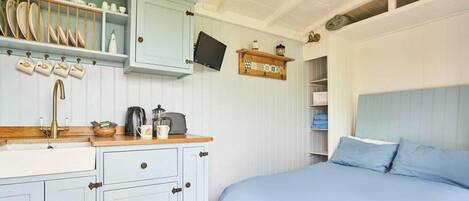 A bedroom with a bed, a nightstand, a dresser, and a window.