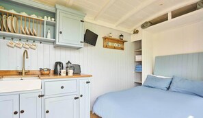 A bedroom with a bed, a nightstand, a dresser, a mirror, and a shelf with kitchenware. - Host Stay Shepherds View (Harleston)