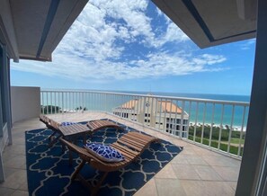 Ein Balkon mit Meerblick, einem Tisch mit Stühlen und einem gemusterten Teppich.