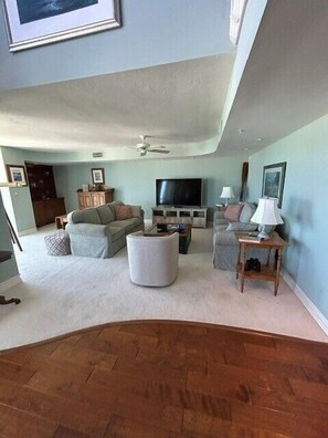 Ein Wohnzimmer mit Fernseher, Sofas, Couchtisch und Deckenventilator.